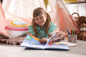 Little girl reading book in wigwam indoors © New Africa