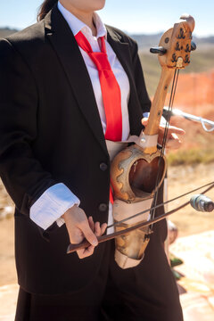 Musician in modern black suit playing traditional kazakh kobyz instrument close up
