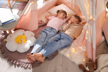 Little girl and boy lying in wigwam at home © New Africa