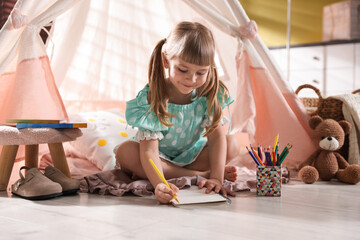 Little girl drawing near wigwam at home © New Africa