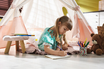 Little girl drawing near wigwam at home © New Africa