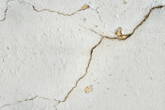 Cracked white wall with peeling paint in a textured pattern.