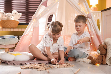 Little girl and boy playing with building blocks in wigwam at home © New Africa