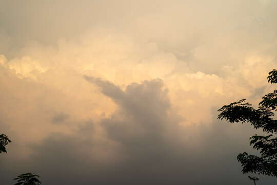Dramatic sunset clouds illuminated with warm hues against a soft gray sky.