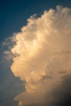 A majestic cumulus cloud against a blue sky at dusk.