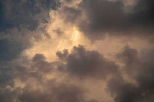 Dramatic cloudscape with golden light peeking through dark storm clouds.