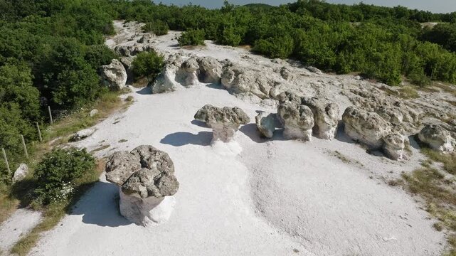 Stone Mushrooms rock formations in Beli Plast volcanic tuff geological landmark white limestone pillars green trees summer day aerial drone view Bulgaria