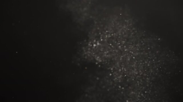 Slow motion real dust flow over dark background