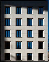 Obraz premium Modern Facade with Geometric Windows A stark, contemporary building facade showcases a repeating pattern of identical windows.