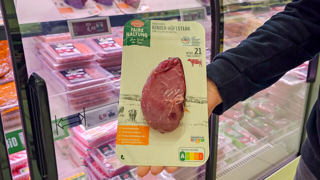 Customer hand holding packaged beef steak in supermarket