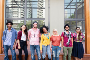 Obraz premium Group of diverse young adults smiling outside a modern building.