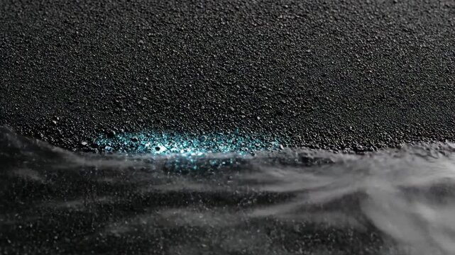 Bioluminescent waves washing onto dark volcanic sand shore. Night ocean water with blue glowing microorganisms hitting black beach. Marine nature phenomenon concept