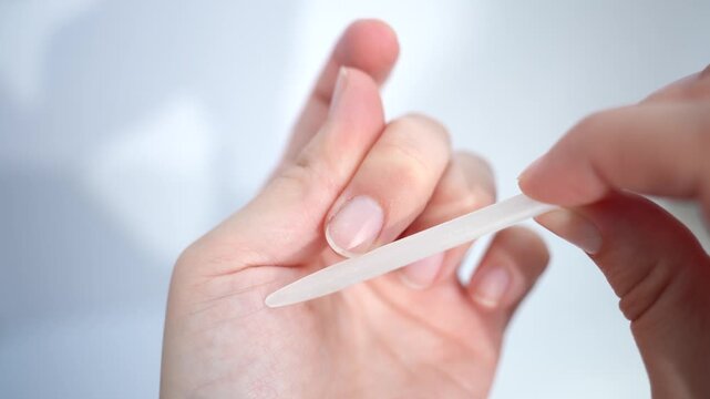 close-up of a woman's hands doing a manicure with a nail file