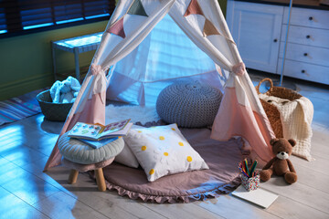 Beautiful wigwam, cushions and toys in child's room at night © New Africa