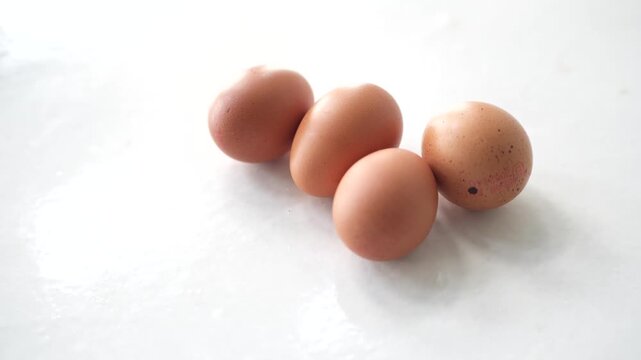 fresh brown chicken eggs resting on a clean white surface in a minimalist composition. The image highlights the simplicity of natural ingredients, making it ideal for cooking, baking