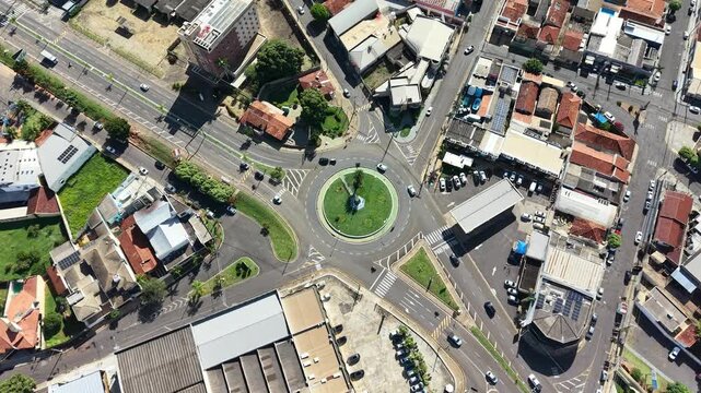 Aerial view of a busy roundabout intersection in a residential and commercial urban area with cars and buildings