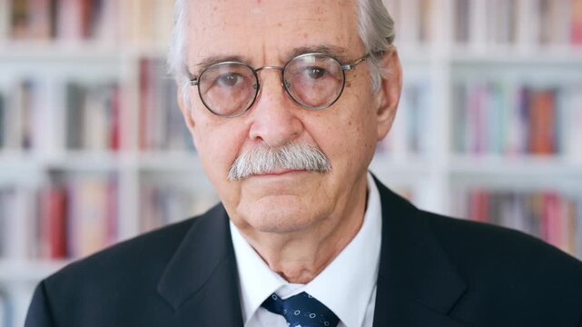 Glasses, professor and face of man in library for about us, course lecturer and faculty manager. Education, university dean and bookshelf with mature person for pride, teacher and college advisor
