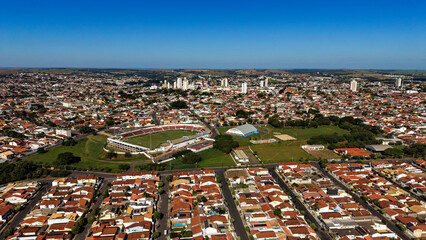 Obraz premium Aerial view of a sprawling city with a stadium and residential areas under a clear blue sky