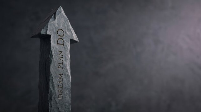 Stone arrow sculpture with dream plan do inscription symbolizing success and goal setting on a dark textured background