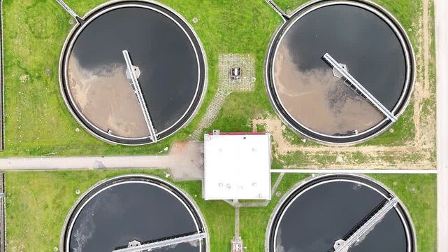 Aerial view of municipal wastewater treatment plant showing multiple circular tanks, filtration systems, and surrounding green areas, highlighting the infrastructure and operational layout of the faci