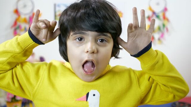 Closeup portrait of a boy mocking - facing the camera. Making funny faces with his tongue out. little cute boy showing a bad behavior looking into the camera - kids negative expression