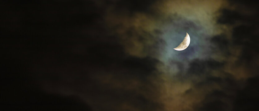Partial moon in the sky glowing through thick clouds