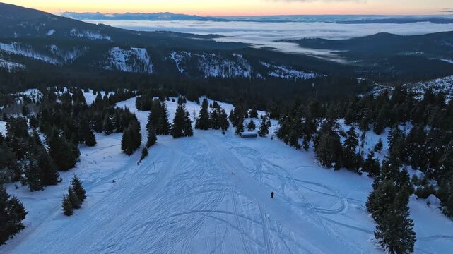 Aerial reverse tilt up shot revealing hiker silhouette on mountain meadow before sunrise with Tatra peaks