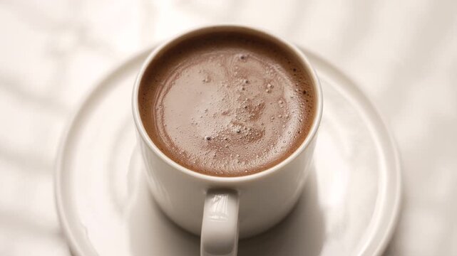 Traditional Turkish coffee in a white porcelain cup spinning on a large white plate, fa01