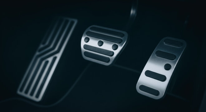 Close up of metallic car pedals in a dark vehicle interior representing performance driving and automotive control