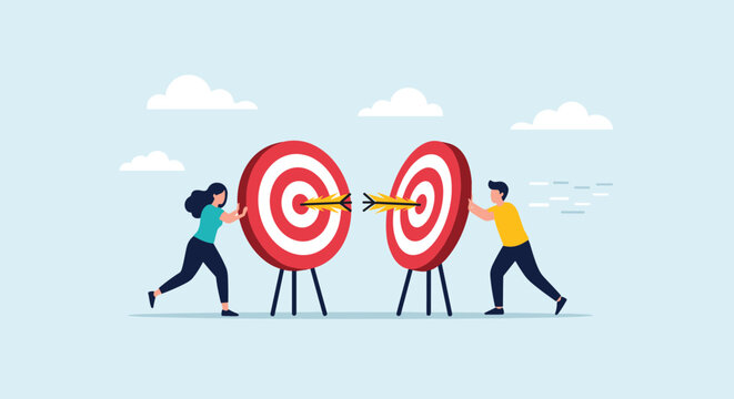Two people work together to push two large targets with arrows in them toward each other representing merging goals and team alignment.