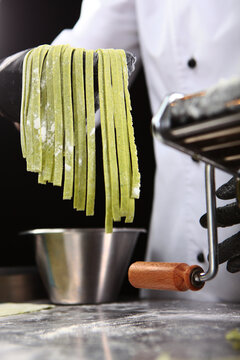Chef prepares dough with spinach. Machine for making pasta and rolling out dough. Homemade pasta. Cooking pasta with spinach