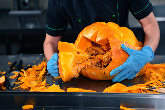 Pumpkin carving. Master carves scary face out of pumpkin. Artistic slicing of vegetables for Halloween decorations. Decorating festive tables and creating spectacular compositions for banquets