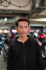 Fototapeta premium Portrait of a Confident Southeast Asian Man with Dyed Hair in a Blurred Parking Garage