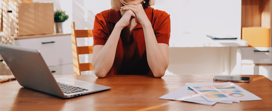 Young woman works on a touchpad, feeling comfortable at cozy home office with a green plant on the background