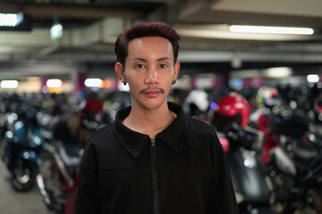 Non-binary gay Thai man from Isan standing inside a motorcycle parking garage, portraying authentic gender fluid identity, nonconforming pride, and genuine queer urban lifestyle. © Ranta Images