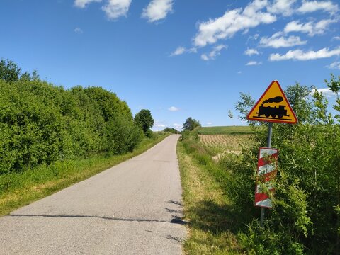Droga wiejska z ostrzegawczym znakiem przejazdu kolejowego