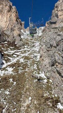 Chairlift ride in Colle Santa Lucia, Dolomites, Italy. Scenic ascent through dramatic alpine cliffs in the Dolomiti Superski region. Mountain travel and outdoor adventure