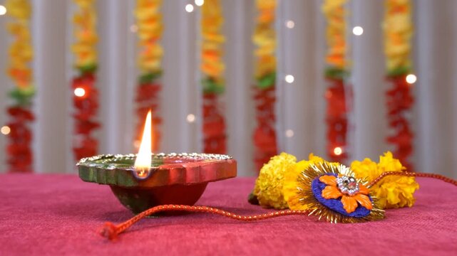 Pan shot of a beautiful rakhi and a light up diya on Raksha Bandhan festival. Closeup of a handmade rakhi  symbol of love between brothers and sisters with a burning diya - Indian festival