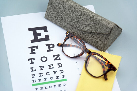 Eye test chart and glasses on blue background