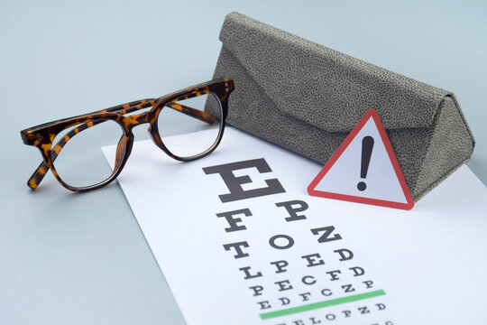 Eye test chart and glasses on blue background