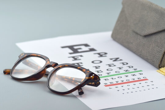 Eye test chart and glasses on blue background
