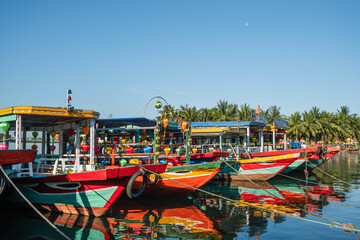 Colorful wooden tourist vessels docked on a calm river © Александр Коноплев