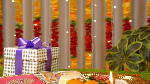 A tilt shot of a decorated puja thali for the Raksha Bandhan celebrations. A beautifully decorated Raksha Bandhan thali contains rakhi  tikka  rice  diya  flowers  sweets  Indian rupee notes and gi...