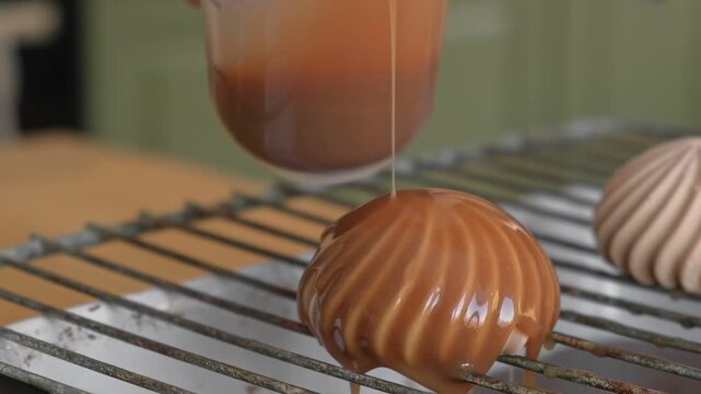 Beautiful mousse cake is drizzled with mirror glaze on grate. Closeup Glazed mousse dome dessert with caramel chocolate decorated with dripping shiny ganache poured drips. Smooth sponge biscuit