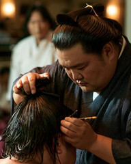 Fototapeta premium Sumo Wrestler's Traditional Hairstyle Preparation - An Insight into Japanese Cultural Heritage and Craftsmanship