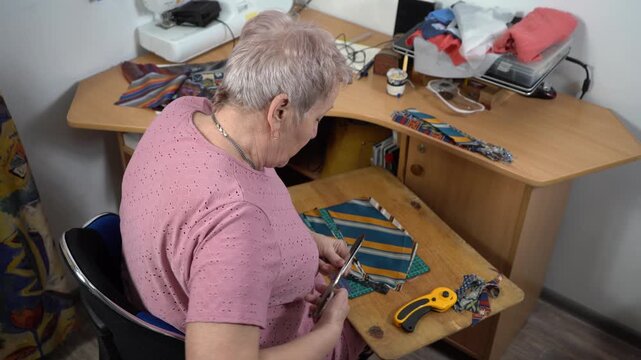 Senior woman sew a patchwork quilt. Needlework sewing.