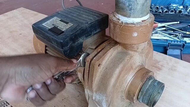 Close-up view of a technician using a spanner to remove the casing bolts of a flood-damaged 1.5KW centrifugal water pump.