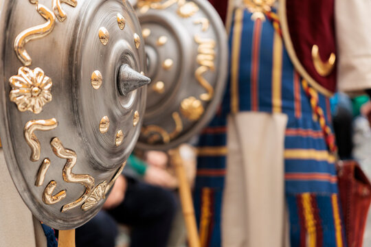 Detalles en primer plano de escudos metalicos con relieves dorados y trajes bordados en las fiestas de moros y cristianos