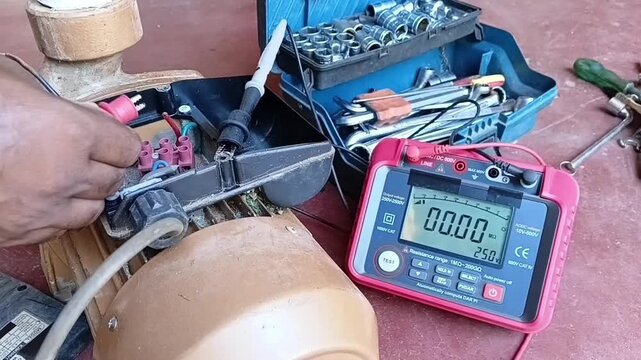 A technician performing an insulation resistance test on a flood-damaged electric water pump using a digital multimeter, showing a failed result.