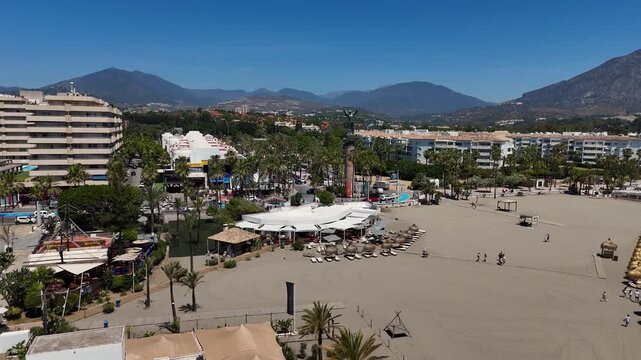 Marbella beach parasols loungers sand resort tourism aerial 4K coastal